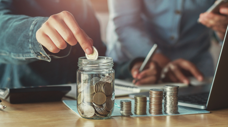 a hand putting coins to a jar